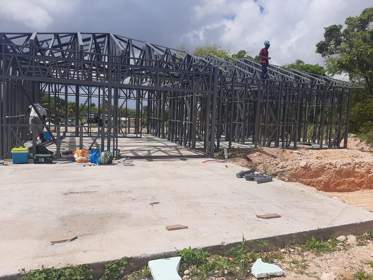 Montage d'une charpente acier avec un ouvrier sur la structure